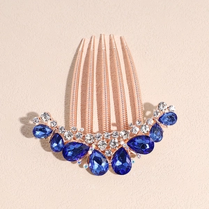 Detail of vintage golden hair comb featuring blue teardrop rhinestones and clear crystals
