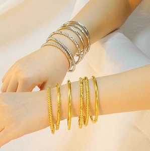 Close-up of elegant 18K gold and silver plated titanium steel bangles on a woman's wrist