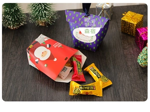 Close-up of Santa Claus and Christmas tree gift boxes with handles on wooden table