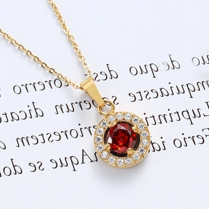 Macro shot of 18K gold plated necklace featuring a round red zircon and pavé crystals