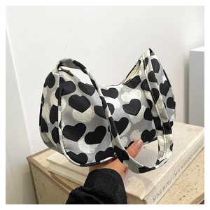 Détail du sac baguette en toile avec motif de cœur noir et blanc et bandoulière souple