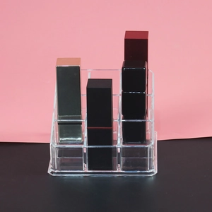 Close-up of clear acrylic lipstick organizer with multiple slots on a pink background