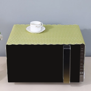 Detail of light green polka dot microwave dust cover with decorative wavy scalloped edges