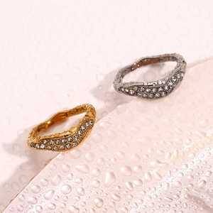 Macro shot of 18K gold and silver wavy eternity rings with inlaid sparkling zircons