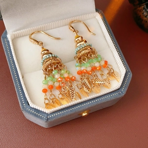 Detail of vintage gold tassel earrings with colorful beads and leaves in velvet box