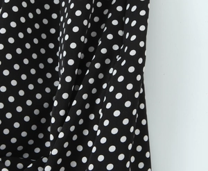 Détail du tissu vintage noir à pois blancs avec une texture fluide et drapée