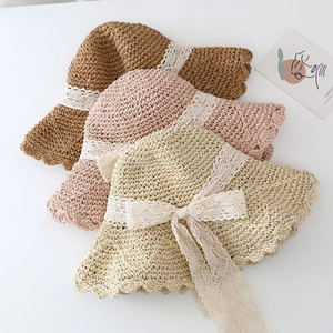 Detailed flat lay of three woven straw hats with lace ribbons and wavy brims in soft colors