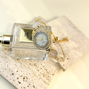 Detail of gold flower bracelet watch with rhinestone bezel and mother-of-pearl dial