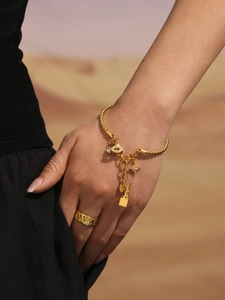 Detailansicht goldener gedrehter Armreif mit Anhängern und Sternring am Modell