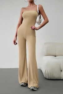 Detail of beige ribbed strapless jumpsuit featuring flared legs with ruffle hem accents