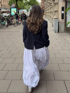 Detail of a chic black cropped blazer with slit back and voluminous white maxi skirt