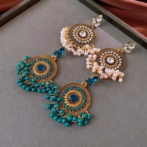 Bohemian dangle earrings with faux pearls and crystals on grey background with silk fabric