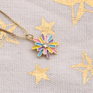Macro view of gold daisy necklace with colorful enamel petals and clear crystal center
