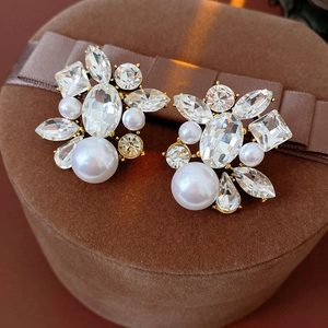 Close-up of vintage drop pearl earrings with rhinestones on a brown velvet box