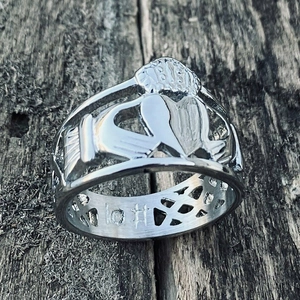 Gros plan détaillé d'une bague Claddagh en argent avec des mains tenant un cœur couronné
