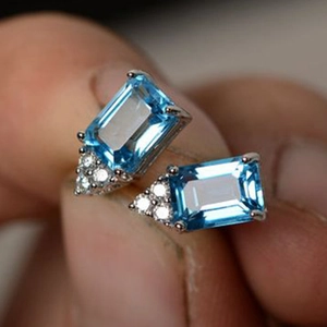 Emerald cut blue topaz stud earrings with small zircon accents in a silver setting