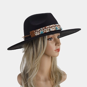 Detail of bohemian fedora hat featuring ethnic tassel band with shell and star pendants