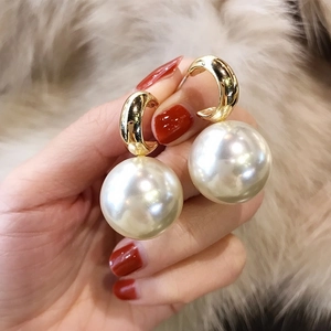 Detailed view of gold C-shaped hoop earrings with large imitation pearl pendants