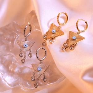 Gold and silver triangle evil eye earrings with zircon drops on silk background