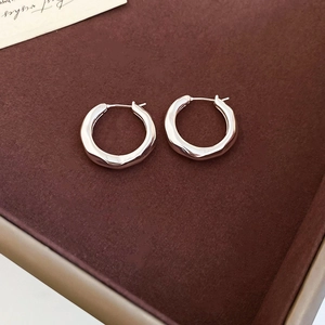 Detailed macro view of silver geometric round hoop earrings with hammered metal texture
