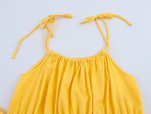 Detail of yellow linen-style dress featuring adjustable shoulder ties and smocked neckline