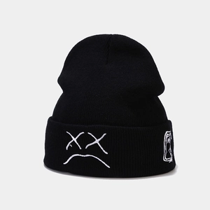 Close-up of black knitted beanie featuring white XX eyes and crying face embroidery detail