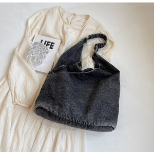 Close-up of black washed denim hobo bag with white stitching detail on a dress