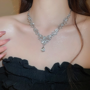 Close-up of silver necklace featuring intricate leaf-shaped crystals and a pear-shaped drop