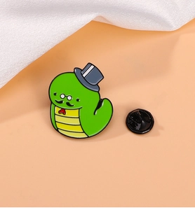 Detail of cartoon green snake enamel pin with top hat, monocle, and rubber clutch