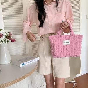 Detail shot of a pink bubble fabric tote bag with textured ruffles held by a model