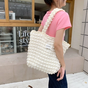 Dettaglio della borsa bianca a bolle con etichetta Love Sozakka su maglietta rosa
