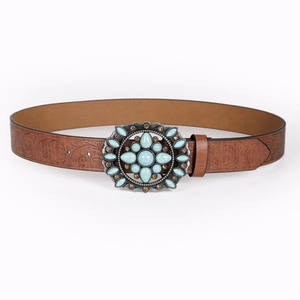 Detail of bohemian brown embossed belt with turquoise gemstone buckle and floral patterns