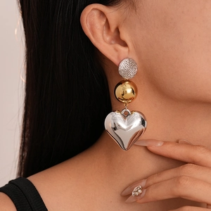 Close-up of geometric metallic heart earrings with gold and silver color-blocking worn by model