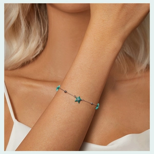 Detail of s925 silver starfish bracelet with teal enamel charms and beads on wrist