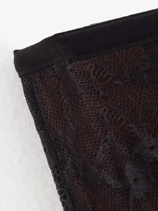 Close-up of the delicate black lace patchwork and fine fabric texture on the trousers