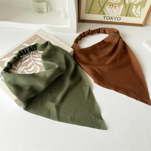 Close-up of vintage silk-like triangle bandanas in dark green and brown on a white desk