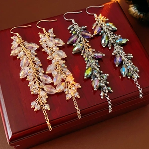 Detail of bohemian tassel earrings with oval crystals on a vintage wooden box background