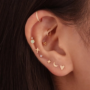 Close-up of gold S925 sterling silver ear studs set with opal and star moon designs