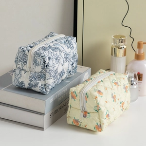 Quilted floral makeup bags in blue and yellow patterns on a minimalist desk setting