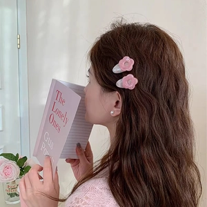 Close-up of pink flower hair clips worn by a model with a soft aesthetic background