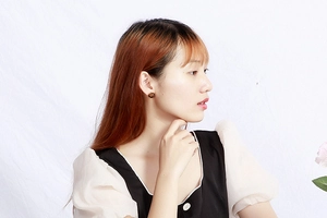 Close-up of elegant black and gold circular stud earrings with radial texture on a model