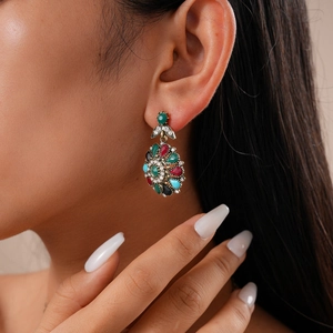 Close-up of vintage teardrop earrings with multi-colored crystals and floral design