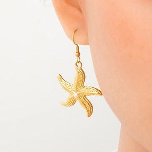 Starfish drop earrings in 18k gold finish with central white pearl on female model
