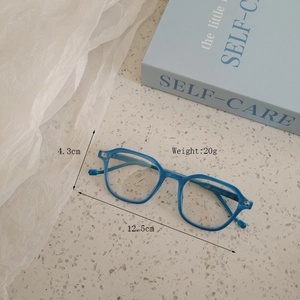 Blue frame kids sunglasses with 12.5cm width and 20g weight on a textured stone desk