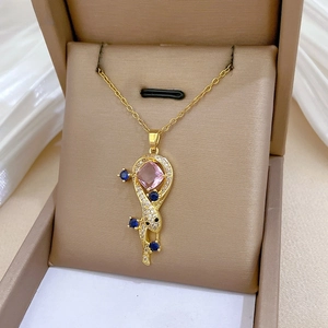Elegant gold snake pendant necklace with pink and blue crystals in a beige jewelry box