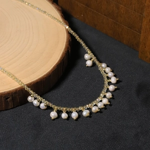 Elegant natural pearl necklace with gold-tone beads and white baroque pearls on wood