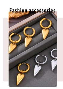 Close-up of heart and triangle charms on gold and silver hoops over jewelry box