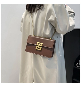 Détail du sac bandoulière en cuir marron foncé avec boucle dorée et bandoulière chaîne