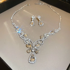 Macro detail of silver floral teardrop pendant necklace and matching diamond earrings set