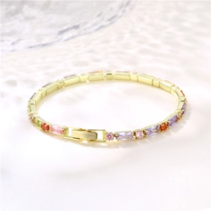 Golden bracelet with colorful rectangular crystals and fold-over clasp on white surface